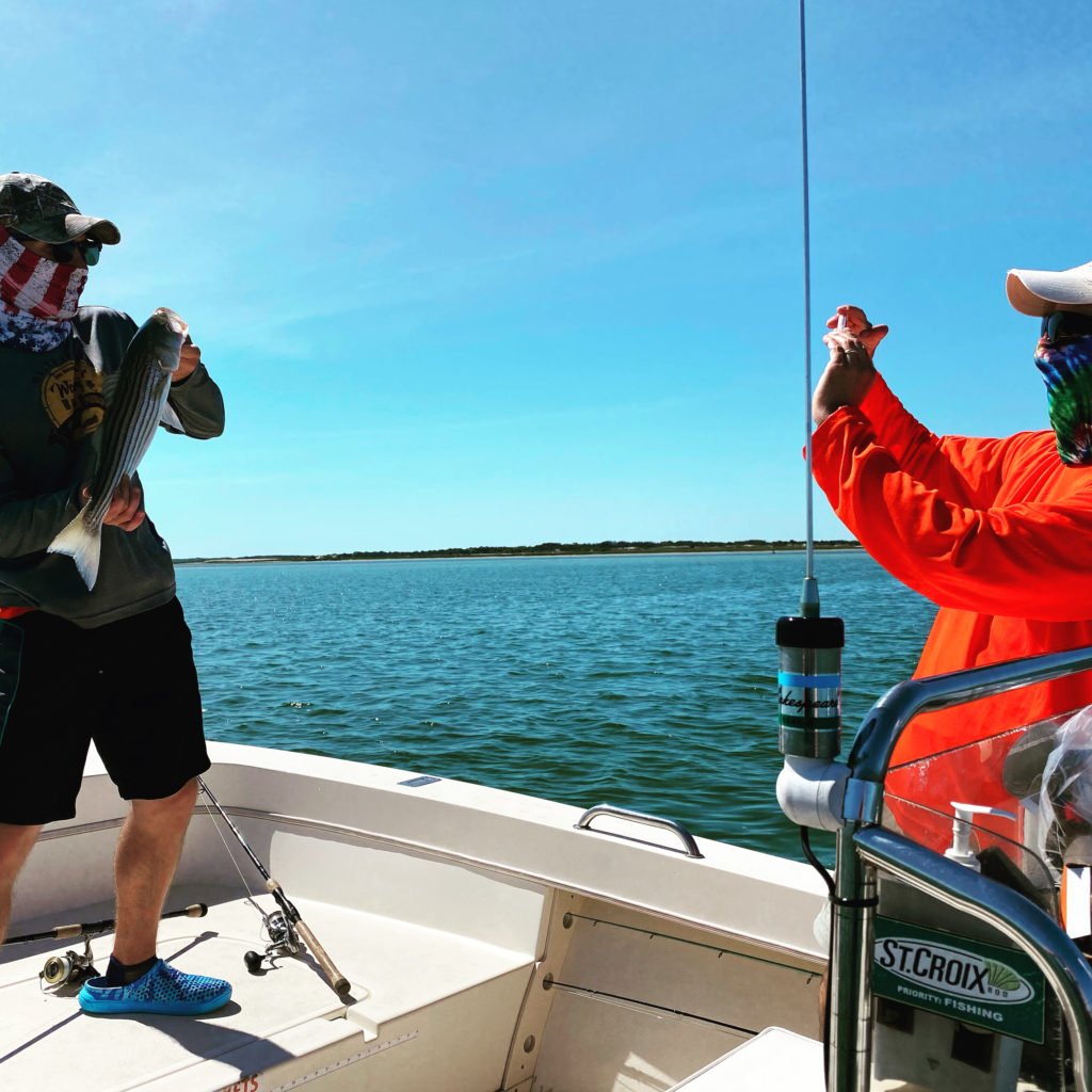 Picture of man taking a picture of boy holding a fish.  fishing with masks...