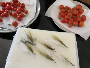 olive & white clouser flies next to red tomatoes