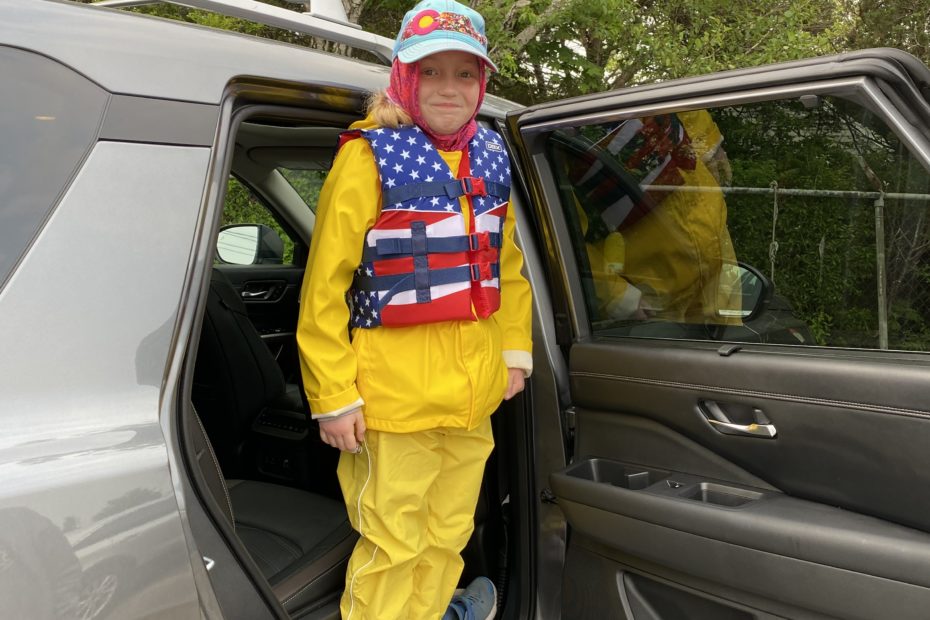 Young girl in a red white and blue life jacket and yellow rain gear