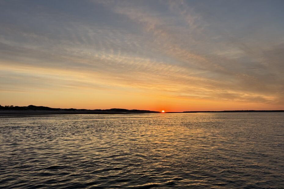 Morning comes early in this sunrise picture of a beach with an orange sunrise