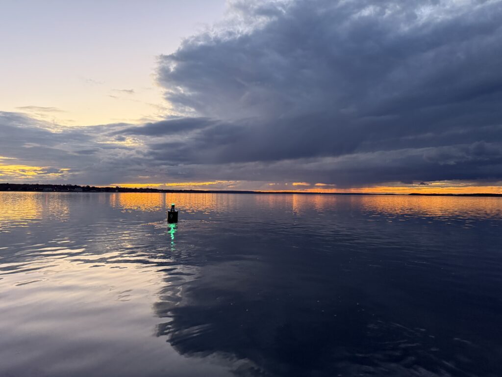 Sunset on Barnstable Harbor with buoy with a green light.